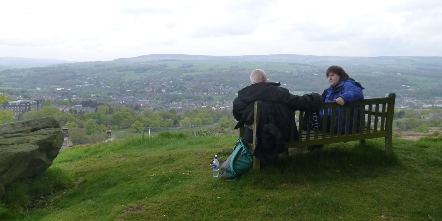 Two colleagues sitting together talking outdoors overlooking the countryside
